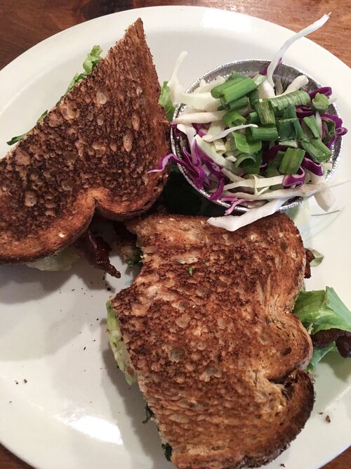 BLT sandwich with a bite taken and a side of cole slaw at Le Petite Marche in Black Atlanta