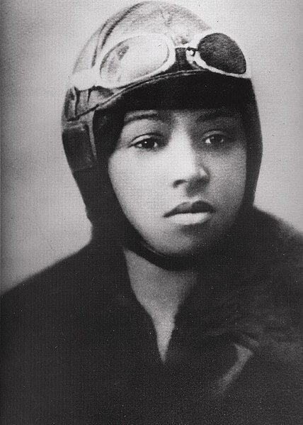 Black and white Bessie Coleman in an old-fashioned aviation helmet with googles on the top