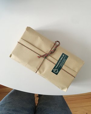 Brown paper wrapped gift with red and green ribbon on a small white round table