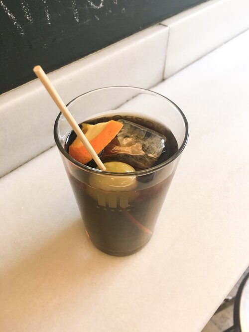 Cold glass of vermouth garnished with an orange slice and an olive