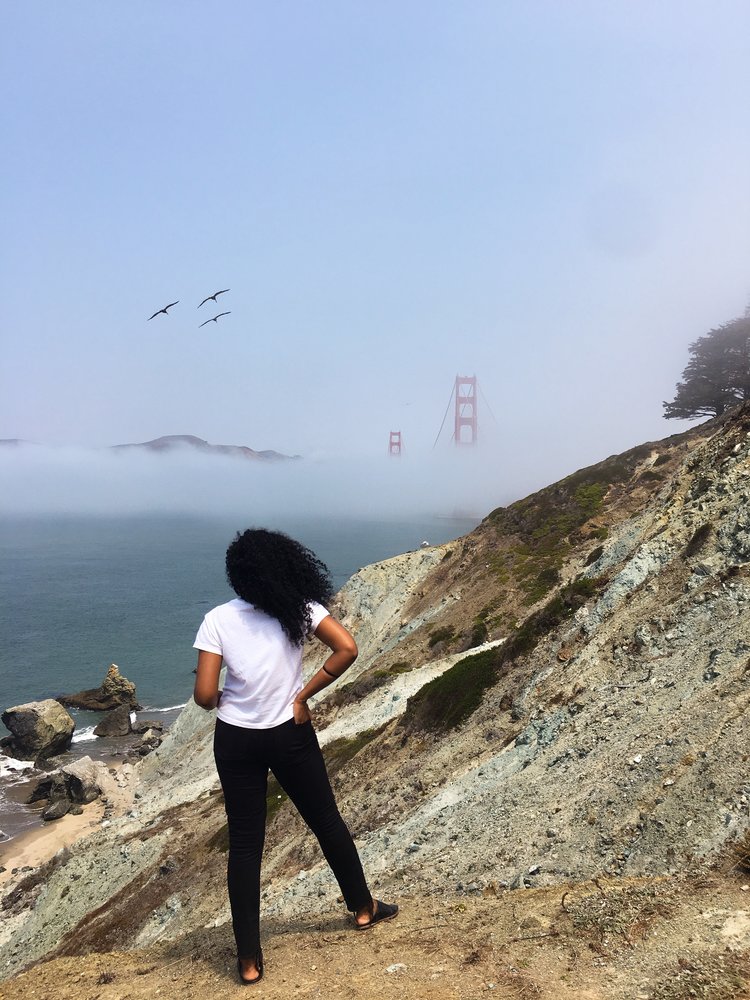 Kim solo traveling and looking out with the wind blowing in her hair at Golden Gat Bridge in San Francisco, California