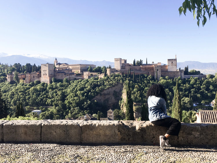 Kim sitting at El Mirador de San Nicolás looking at the views of the Alhambra in Granada Spain