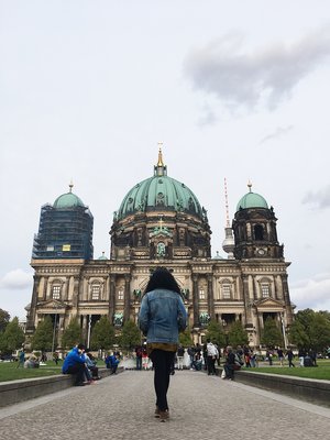Kim in a blue denim jacket and black jeans standing in front of the Berlin Cathedral (Berlin Dom) in Berlin Germany in Europe on a sunny day