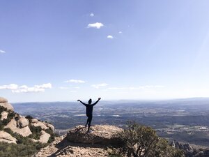 Kim standing on top of Montserrat Mountain with her arm raised in Barcelona Spain