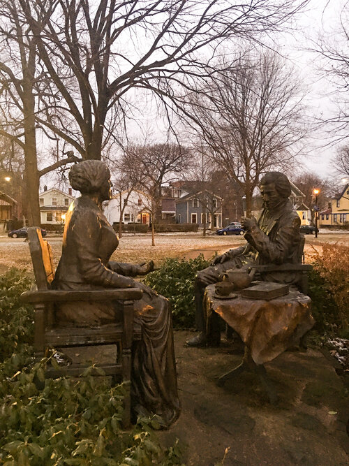 Let’s have tea statue in Susan B Anthony Square in Rochester New York at dusk