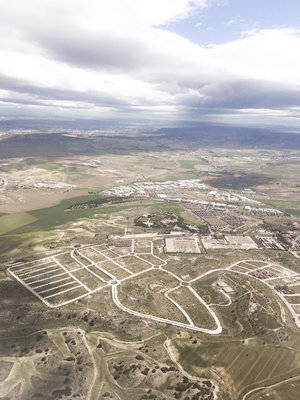 View from plane of green and brown grass and dirt roads