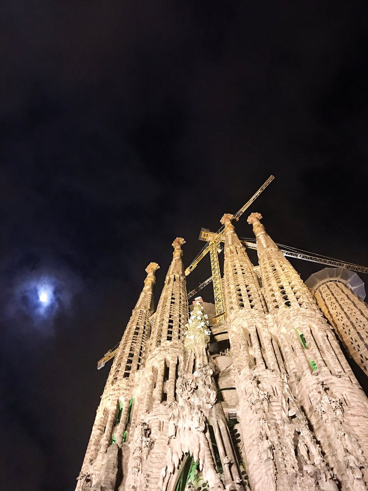 Looking up at La Sagrada Familia towers at night with the moon in the sky