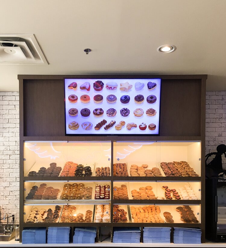 Main glass doughnut case with lots of delicious donuts and framed photo of donuts at Sublime Doughnuts in Atlanta Georgia