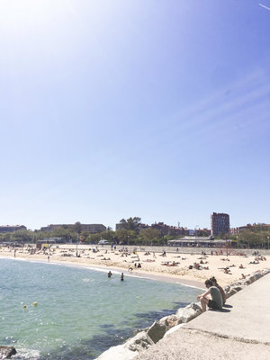 People sitting and enjoying the sun at Barceloneta beach in Barcelona Spain