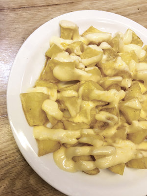 White plate of hot patatas bravas drizzled with a creamy bravas sauce
