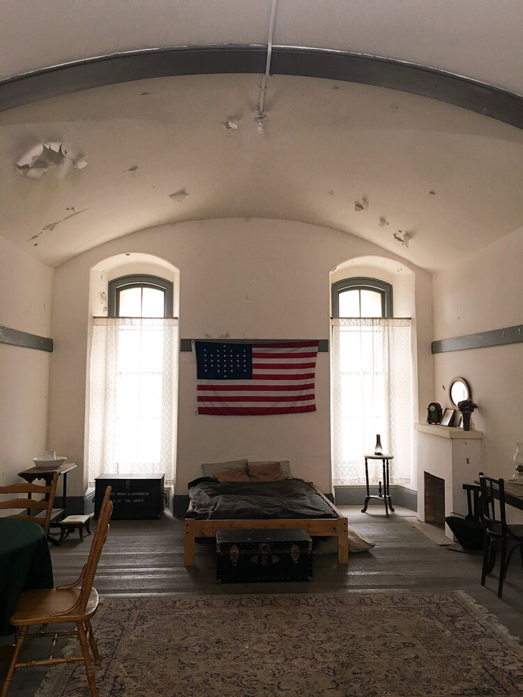Recreated soldier bedroom from the war with a bed and old American Flag at Fort Point