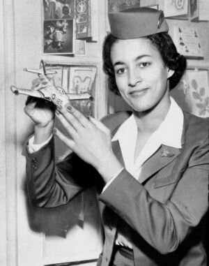 Black History woman Ruth Carol Taylor in an old-fashioned flight attendant uniform holding a toy airplane