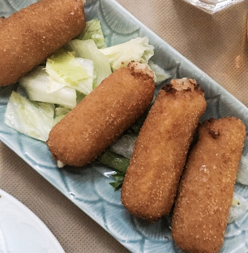 Small light blue rectangular plate with the popular tapas four crispy chicken croquettes garnished with iceberg lettuce