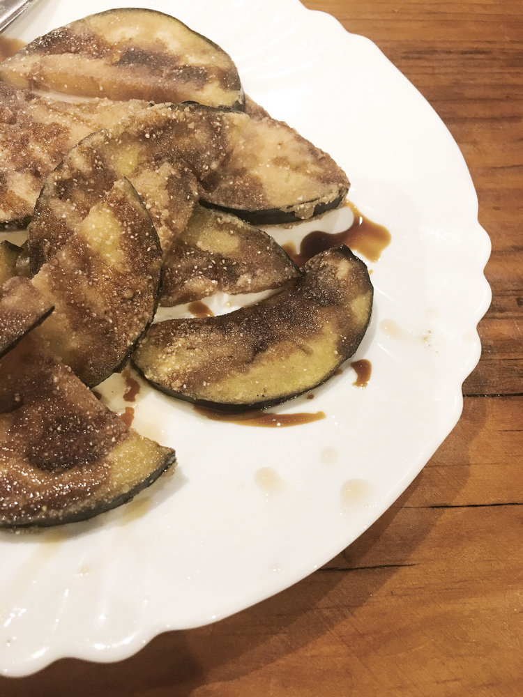 Small white plate with popular tapas fried eggplant drizzled with balsamic vinegar