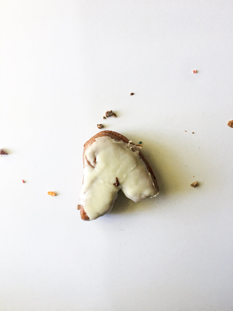 Doughnut in the shape of an A with white frosting and colorful spotted sprinkles