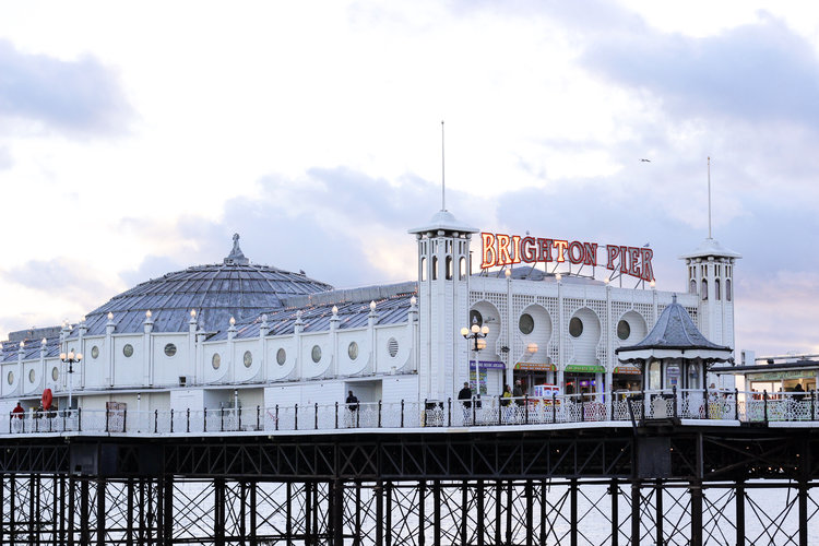 The Brighton Pier with the sign lit up in Brighton England in Europe during sunset