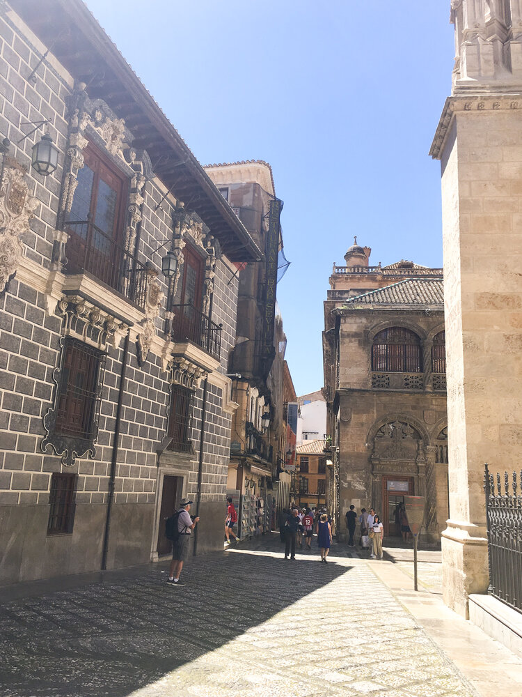 Tourists walking through narrow streets on a sunny afternoon in Granada Spain
