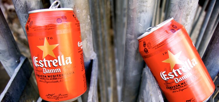 Two bright red cans of Estrella Damn beer