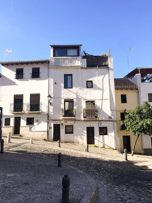 White building with windows on quiet street corner in Granada, Spain on a sunny day