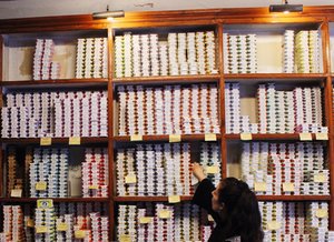 Woman reaching onto high shelf stacked with colorful cans of tuna at Conserveira de Lisboa in Lisbon Portugal