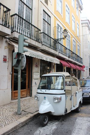 Small light blue electric car with no doors outside of Conserveira de Lisboa in Lisbon Portugal on a sunny afternoon