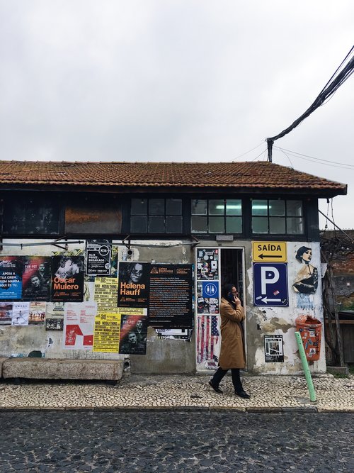 Man talking on a cell phone in front of building with concert posters