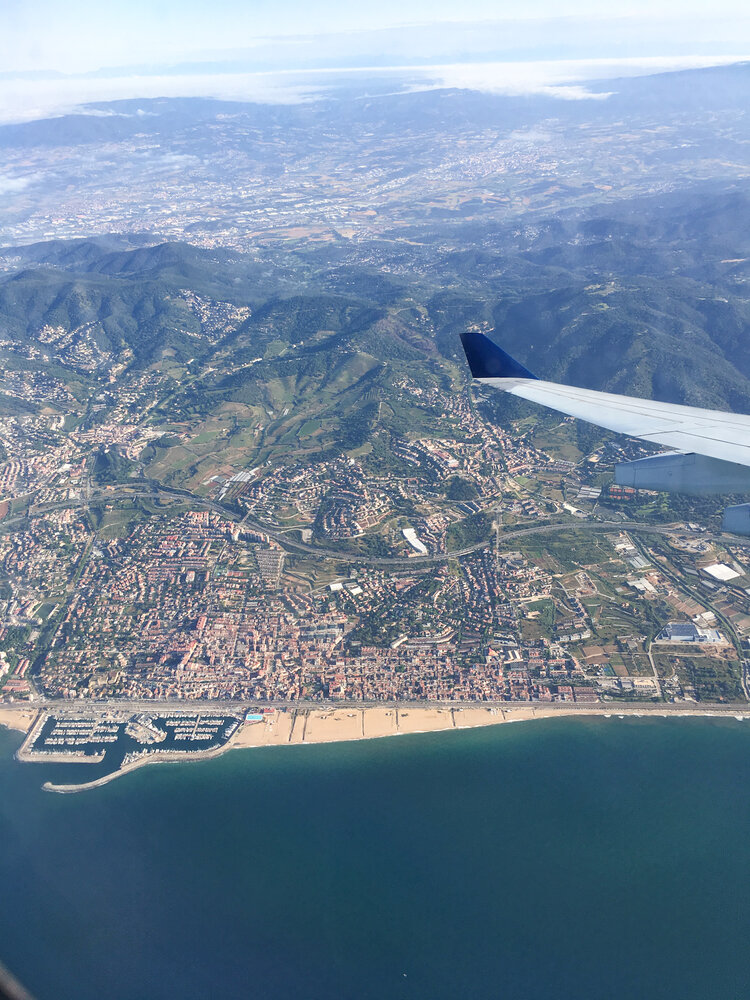 The views of barcelona from above and the side of a plane wing outside the plane window