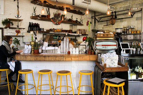 Beautiful interior of The Butcher’s Daughter with yellow bar stools and bright lights in downtown Manhattan