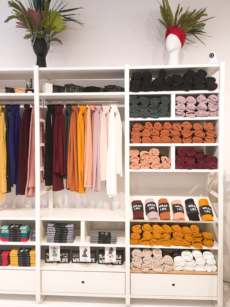 Display inside women owned business The Wrap Life in Brooklyn with colorful wraps hanging up and rolled on the shelf