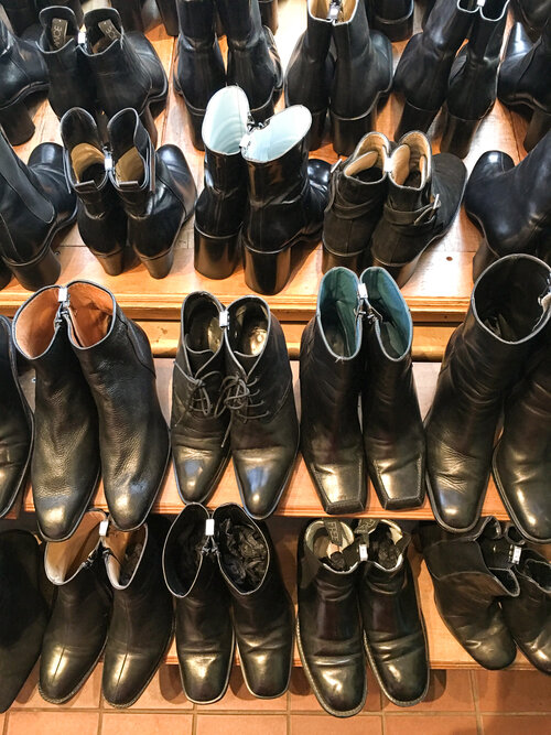 Display of black boots on light brown shelves at women owned business Malin Landaeus vintage store in Brooklyn