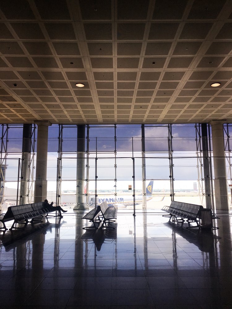 Half empty airport with one person seated and plane outside the window-2