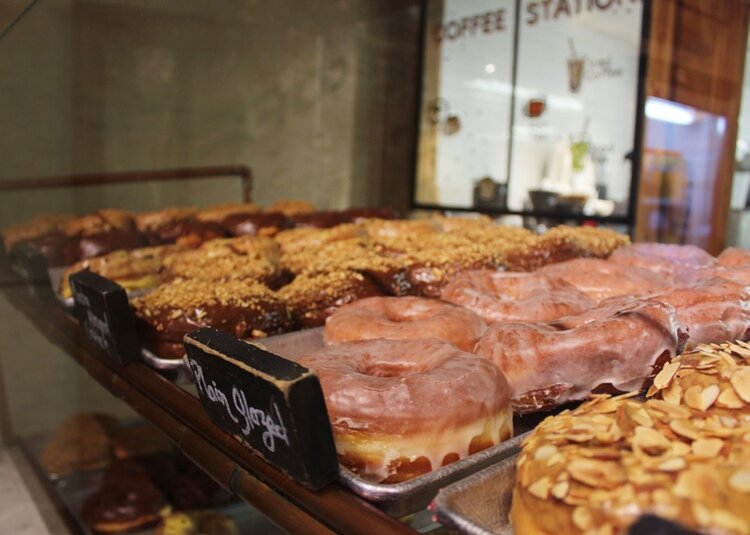 Inside display of Dough doughnut shop with glazed, almond, and chocolate donuts
