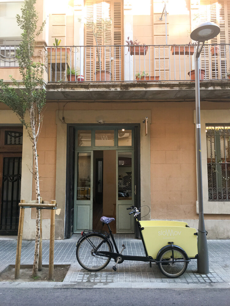 outside of Slow Mov in Barcelona with a pastel yellow bicycle trolly parked in front on the sidewalk