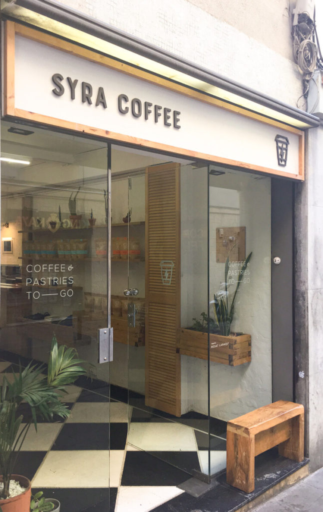 Outside of Syra with small wooden bench in front of the store