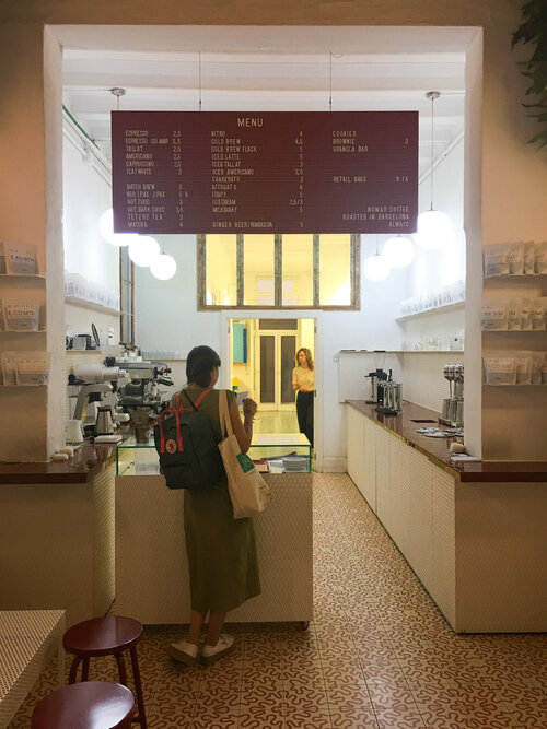Woman standing to order at counter inside of Nomad Coffee Barcelona in Raval
