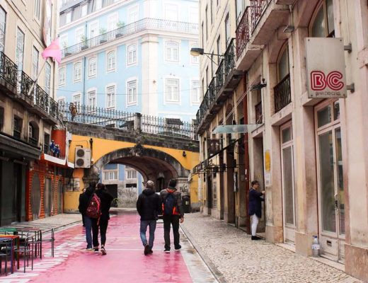 Pink road in lisbon portugal with yellow bride and blue building on a rainy day