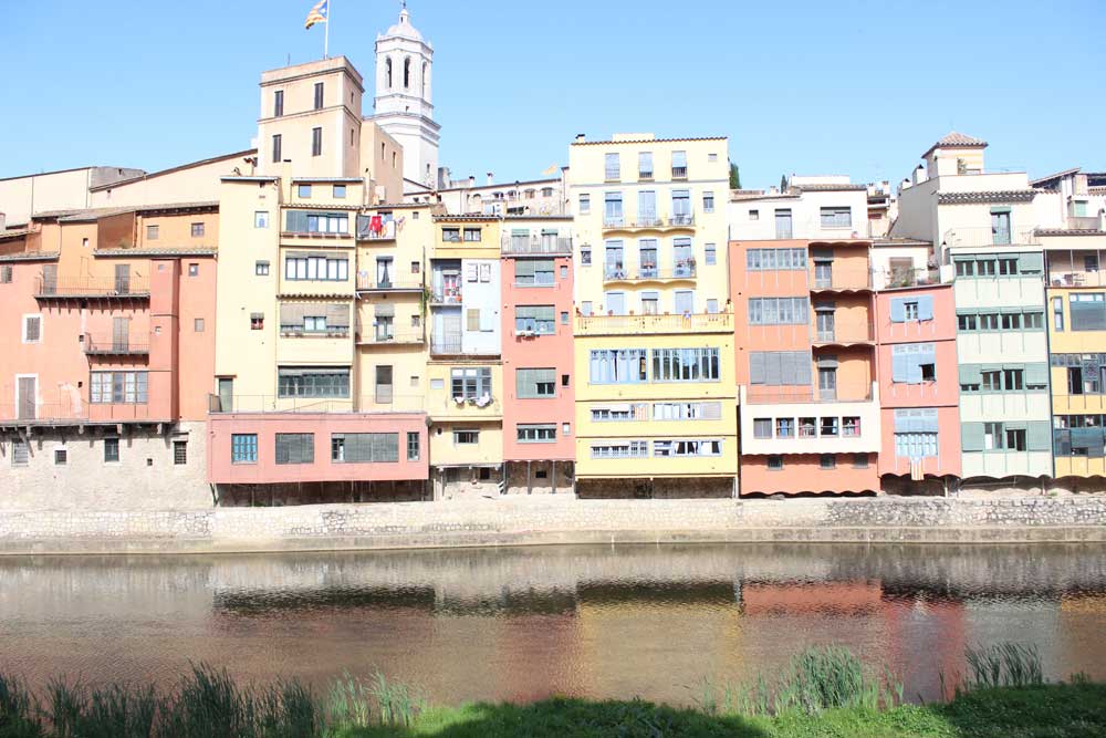 Colorful facade over river in Girona Catalonia in Spain on a sunny day one of the best Barcelona day trips
