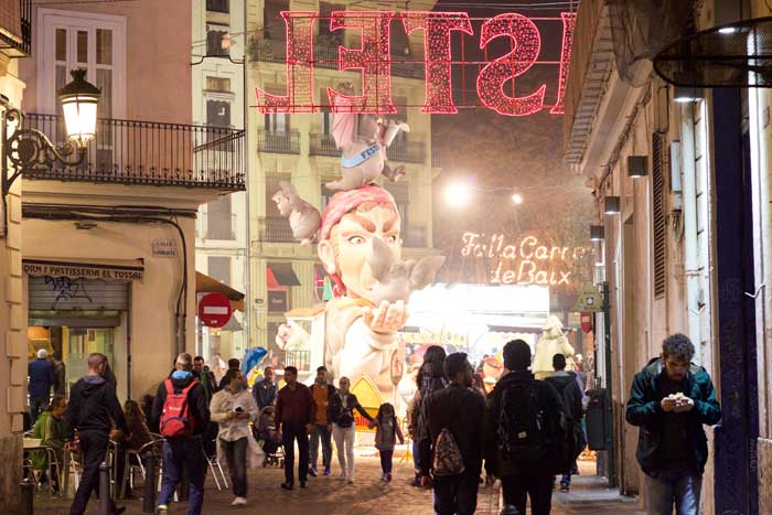 The crowded streets of Valencia at night with floats in the background during las fallas festival