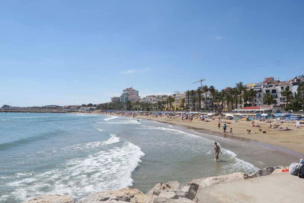The beach in Sitges filled with locals laying out in the sun during one of the Barcelona day trips
