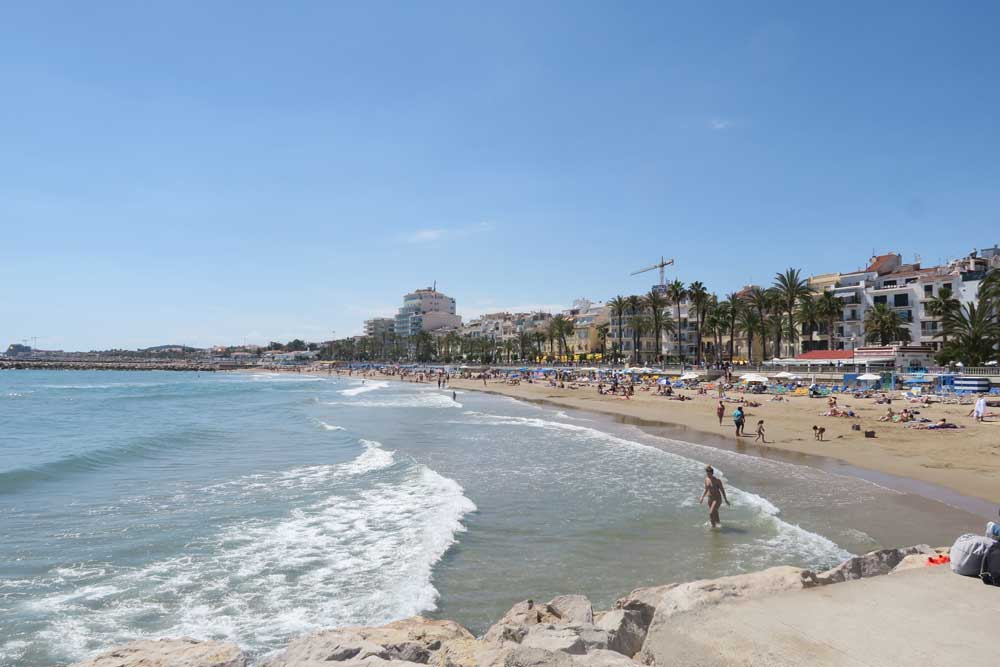 The beach in Sitges filled with locals laying out in the sun during one of the Barcelona day trips