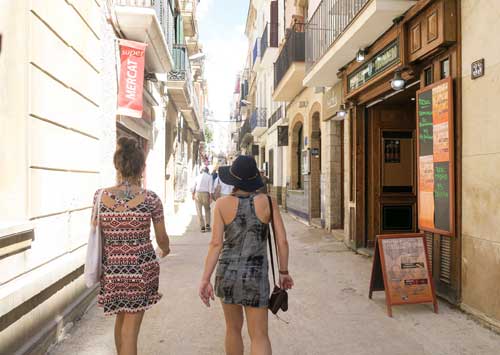 Two girls walking down the narrow streets in Sitges in one of the Barcelona day trips
