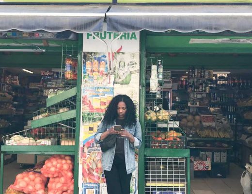 Kim on her phone and standing in front of a colorful fruit stand in Madrid Spain