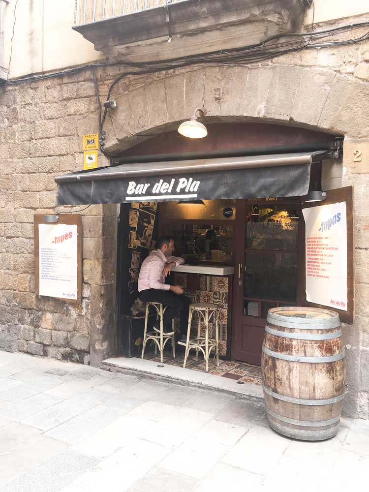 Man sitting at outdoor bar at Bar de Pla one of the best tapas bars in Barcelona