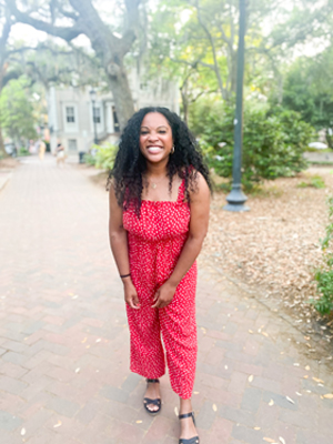 Kim smiling in a red polka dot romper and sandals in Savannah on a sunny afternoon